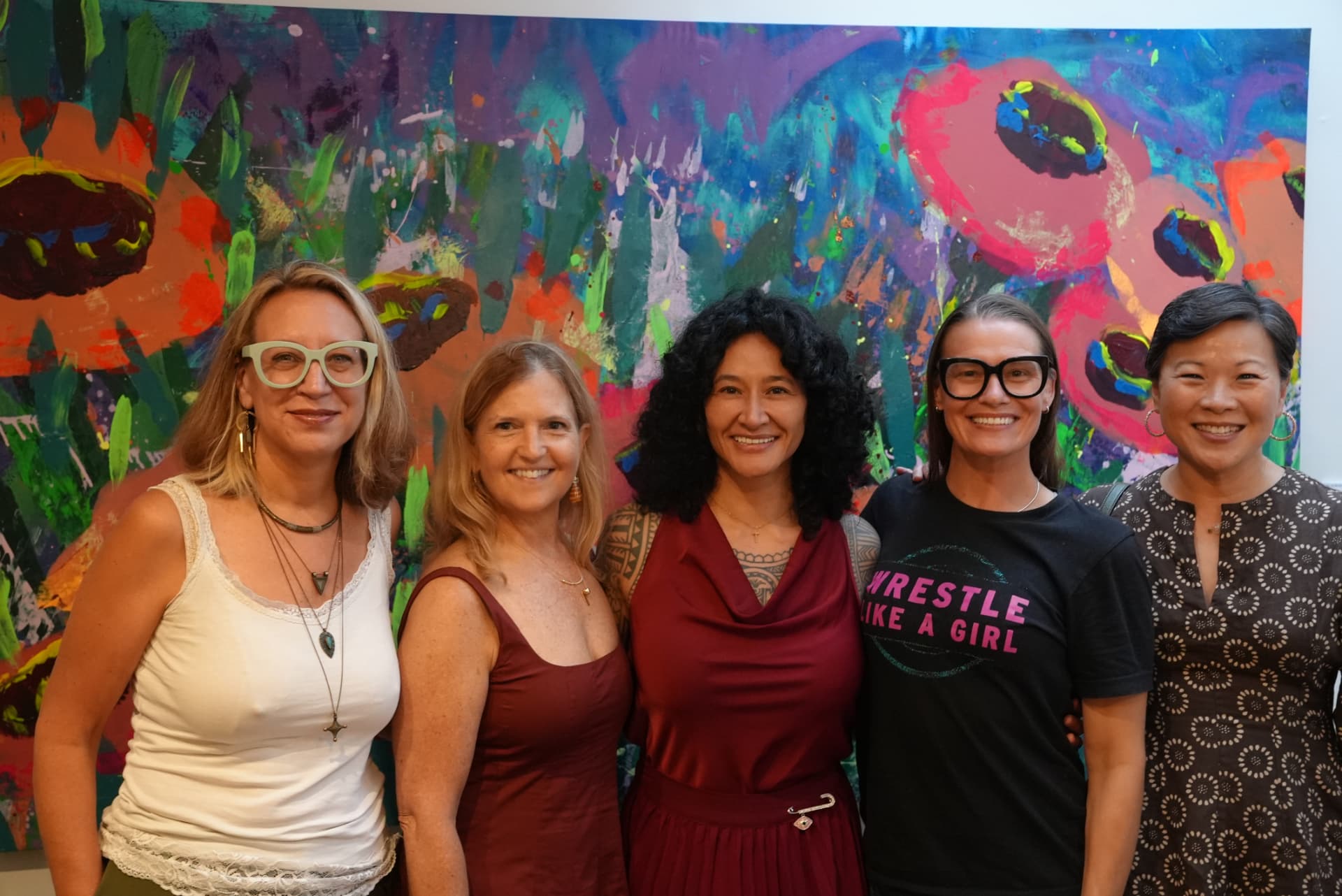 Guests posing in front of a floral painting at the In Bloom opening